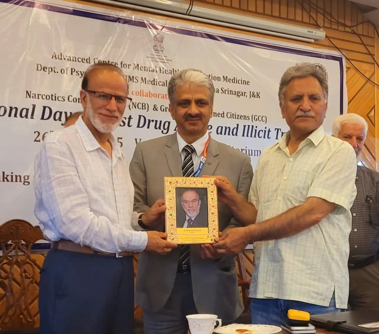 Dr. Mushtaq Ahmad Margoob and colleagues holding a framed recognition plaque